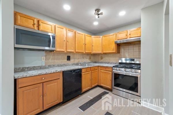 kitchen featuring decorative backsplash, sink, light stone counters, and appliances with stainless steel finishes