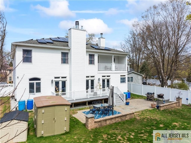 11 Hilltop Blvd N, East Brunswick, NJ 08816 - rear view of property with a balcony, a patio, roof mounted solar panels, and a chimney