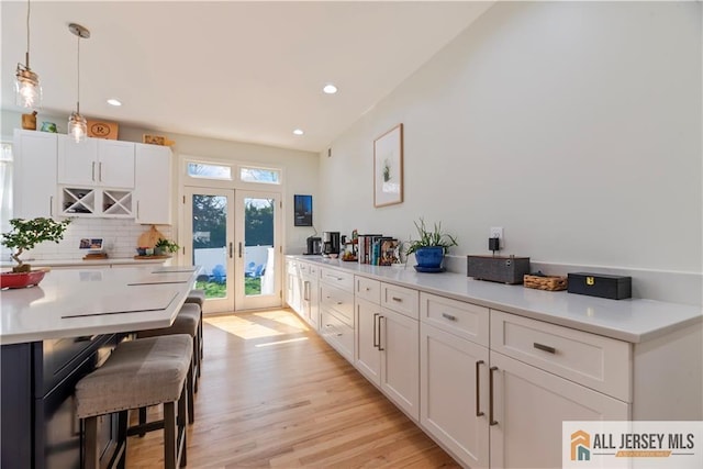 11 Hilltop Blvd N, East Brunswick, NJ 08816 - kitchen featuring french doors, white cabinetry, light countertops, light wood-style flooring, and decorative backsplash