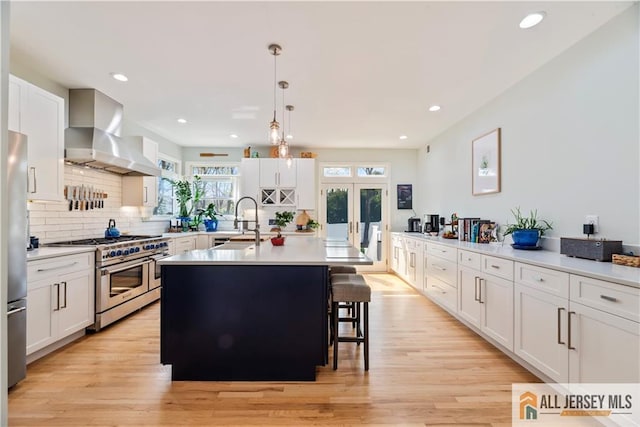 11 Hilltop Blvd N, East Brunswick, NJ 08816 - kitchen featuring appliances with stainless steel finishes, wall chimney exhaust hood, a sink, light countertops, and an island with sink