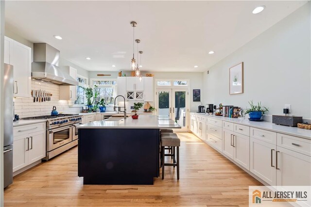 11 Hilltop Blvd N, East Brunswick, NJ 08816 - kitchen with appliances with stainless steel finishes, wall chimney exhaust hood, a sink, light countertops, and a center island with sink