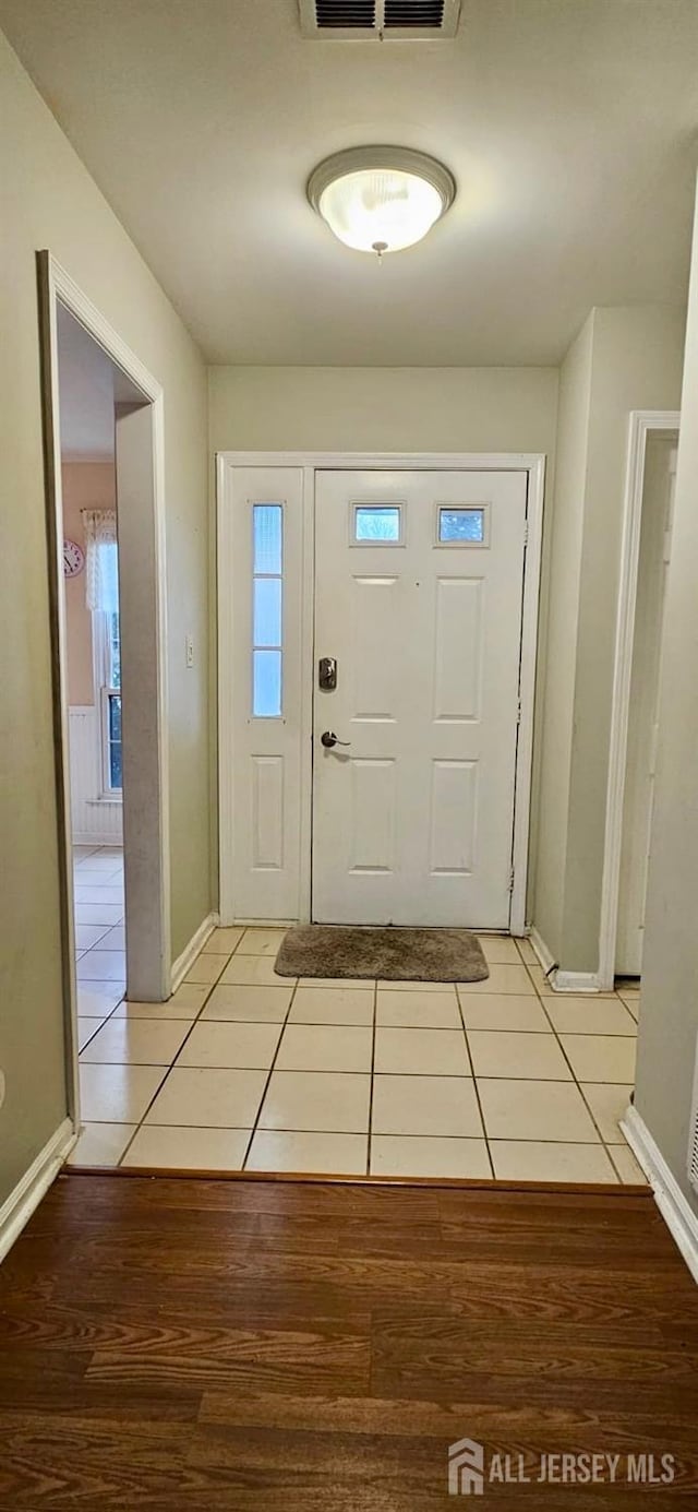 entryway with light tile patterned flooring, visible vents, and baseboards