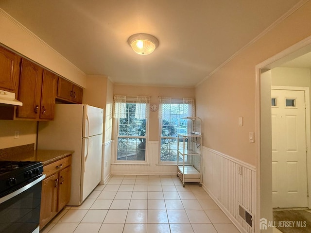 2003 Timber Oaks Rd, Edison, NJ 08820 - kitchen featuring under cabinet range hood, black gas stove, a wainscoted wall, brown cabinetry, and light tile patterned floors