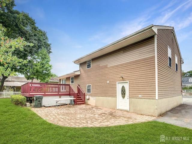 rear view of house featuring a patio, a yard, a deck, and fence