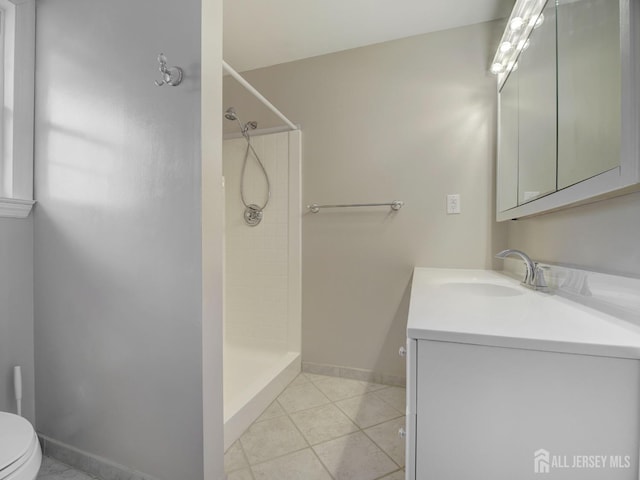 full bathroom featuring tile patterned flooring, toilet, vanity, baseboards, and a shower stall