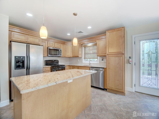 kitchen featuring a center island, visible vents, light brown cabinetry, appliances with stainless steel finishes, and a sink