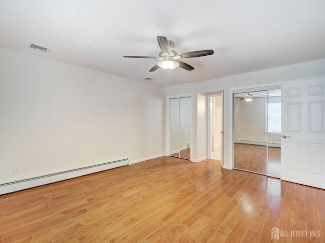 unfurnished bedroom featuring light wood finished floors, a baseboard radiator, visible vents, and two closets