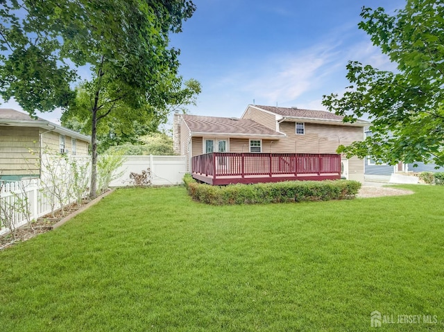 rear view of property featuring a fenced backyard, a lawn, and a wooden deck