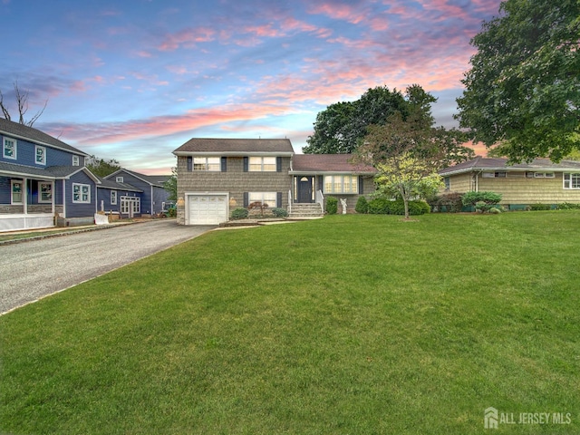 split level home featuring driveway, an attached garage, and a front lawn