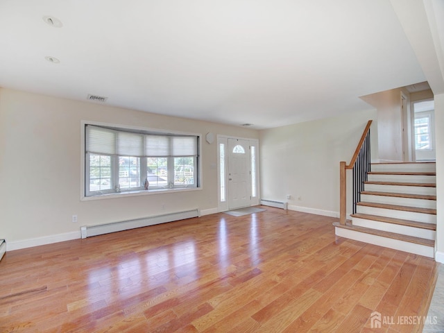 interior space with light wood finished floors, visible vents, a baseboard radiator, stairway, and a baseboard heating unit