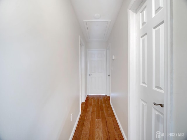 corridor featuring dark wood-style floors, attic access, and baseboards