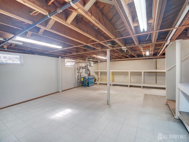 below grade area featuring a heating unit, baseboards, and tile patterned floors