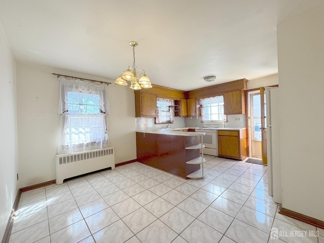 kitchen featuring light countertops, radiator heating unit, a peninsula, brown cabinetry, and electric range