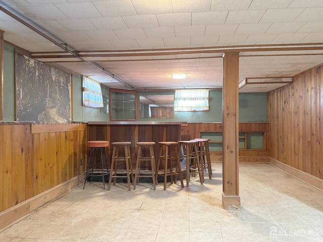 bar featuring a bar, tile patterned floors, and wood walls