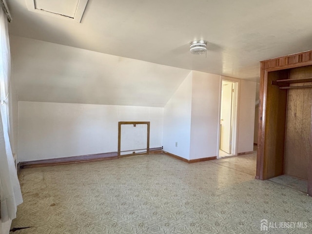 additional living space with baseboards and vaulted ceiling