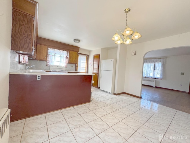 kitchen with white appliances, radiator heating unit, light countertops, and a wealth of natural light