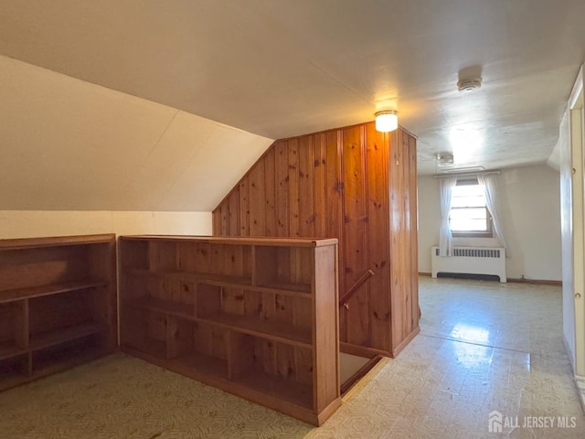 additional living space with tile patterned floors, wood walls, radiator heating unit, and lofted ceiling