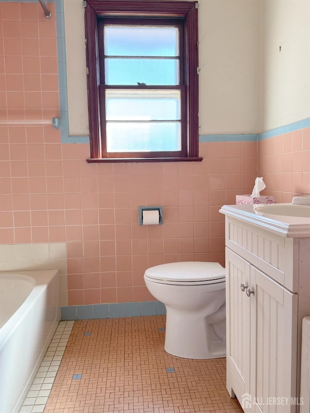 full bath featuring vanity, a bathing tub, tile patterned floors, toilet, and tile walls