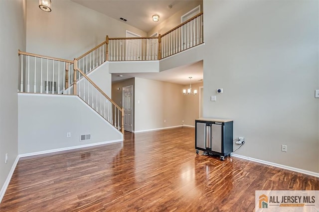 1804 Pheasant Run, South Brunswick, NJ 08852 - unfurnished living room with stairs, wood finished floors, baseboards, a chandelier, and a high ceiling