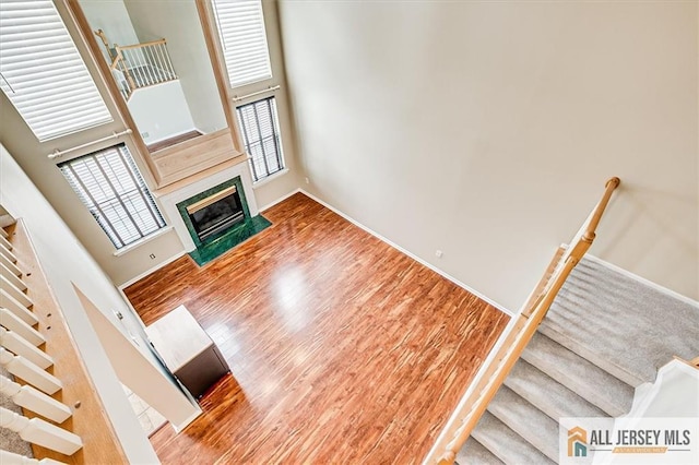 1804 Pheasant Run, South Brunswick, NJ 08852 - unfurnished living room with wood finished floors, a towering ceiling, a fireplace with flush hearth, baseboards, and stairs