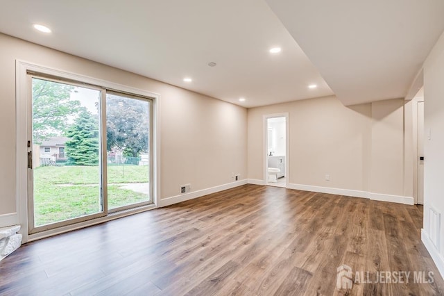 empty room with wood finished floors, baseboards, and recessed lighting