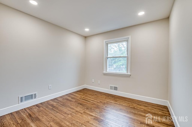 spare room featuring baseboards, wood finished floors, and recessed lighting