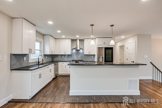 kitchen featuring stainless steel appliances, wall chimney range hood, a sink, dark wood finished floors, and white cabinets