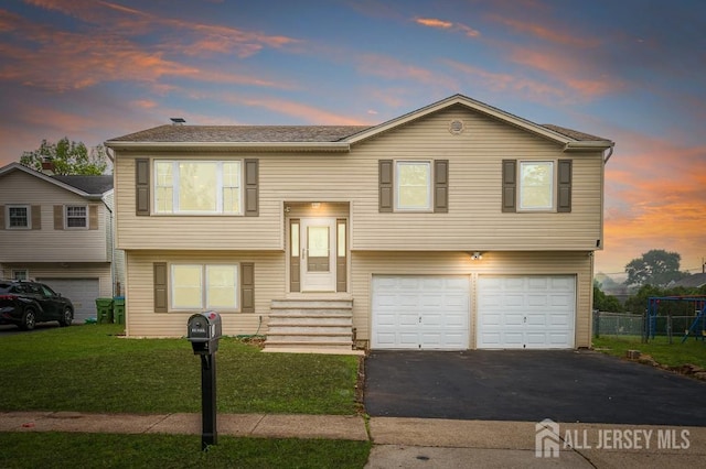 bi-level home with an attached garage, asphalt driveway, and entry steps