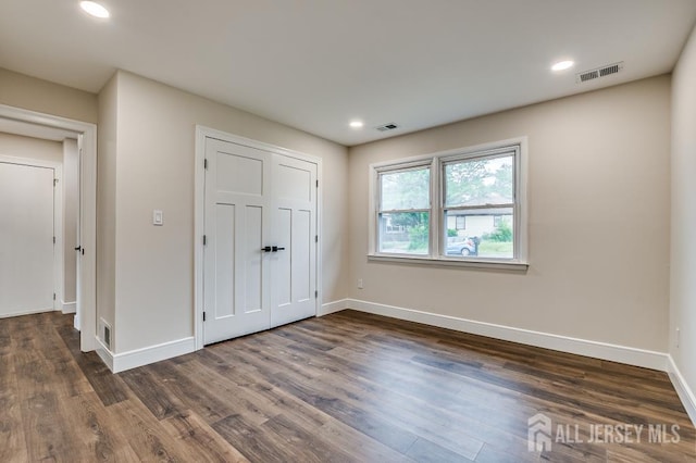unfurnished bedroom featuring baseboards, dark wood-style floors, recessed lighting, and a closet