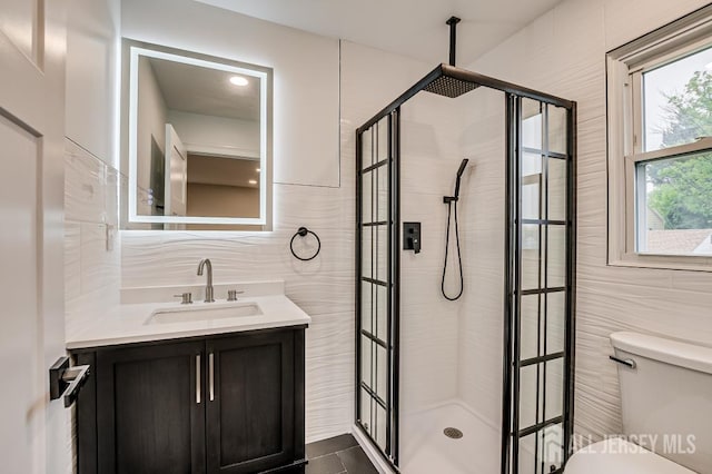 bathroom featuring tile walls, a shower stall, toilet, and vanity