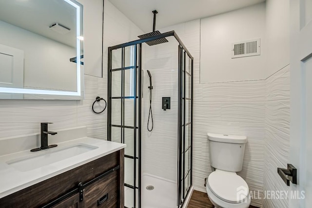 full bath with tile walls, a shower stall, toilet, and vanity