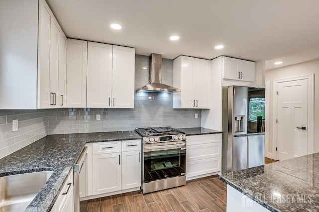 kitchen featuring wall chimney exhaust hood, stainless steel appliances, dark wood-type flooring, white cabinets, and a sink