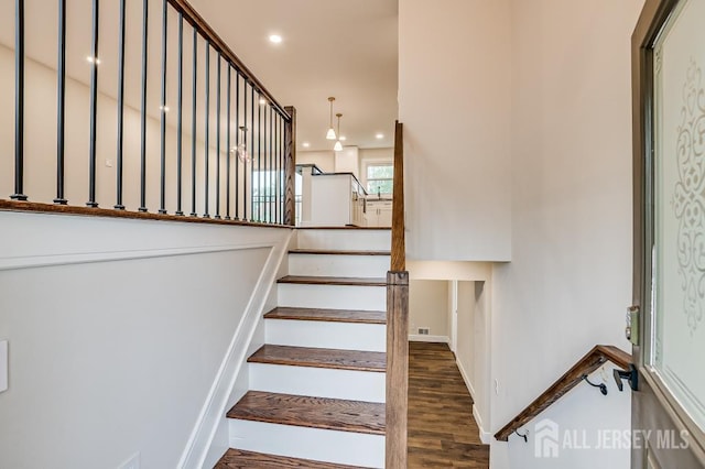 stairs with wood finished floors, recessed lighting, and baseboards