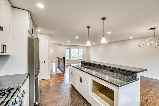 kitchen with appliances with stainless steel finishes, dark wood-type flooring, a kitchen island, white cabinets, and recessed lighting