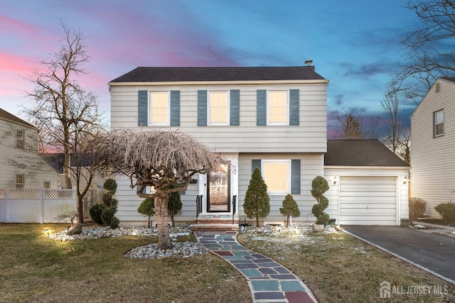 colonial house featuring a garage, a front lawn, fence, and aphalt driveway