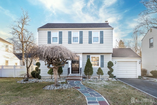 colonial inspired home featuring a chimney, fence, a garage, driveway, and a front lawn