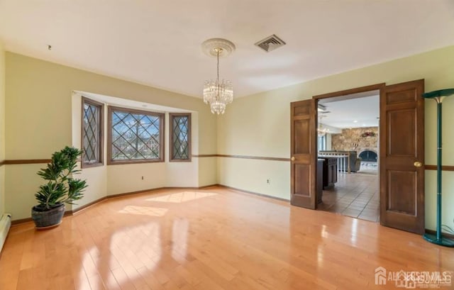 6 Persimmon Ct, East Brunswick, NJ 08816 - unfurnished dining area featuring wood finished floors, a chandelier, and baseboard heating