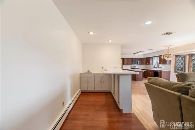 6 Persimmon Ct, East Brunswick, NJ 08816 - kitchen featuring open floor plan, a peninsula, stainless steel microwave, light countertops, and wood finished floors