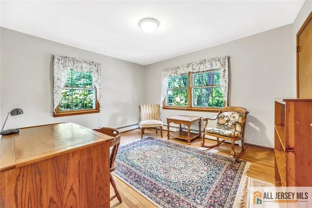 sitting room featuring baseboard heating, light wood-type flooring, and plenty of natural light