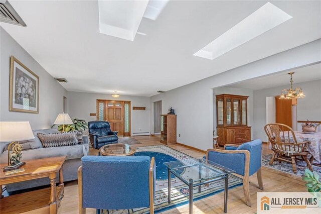 living room featuring light hardwood / wood-style flooring, a skylight, an inviting chandelier, and a baseboard radiator