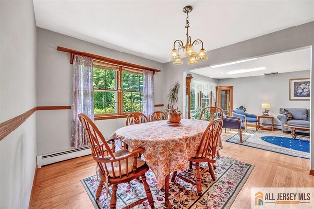 dining room featuring a baseboard radiator, light hardwood / wood-style flooring, and a notable chandelier