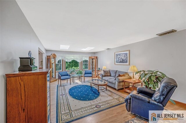 living room featuring light hardwood / wood-style flooring and a skylight