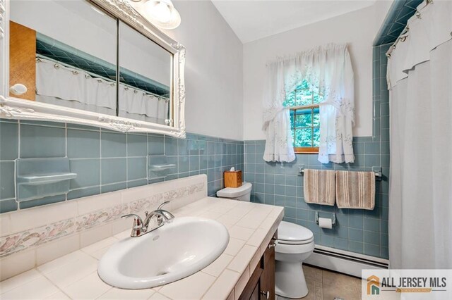 bathroom with baseboard heating, tile patterned flooring, vanity, tile walls, and toilet