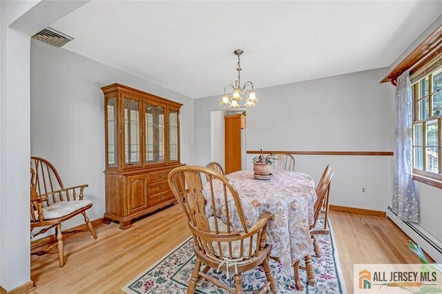 dining space with baseboard heating, light hardwood / wood-style floors, and a notable chandelier