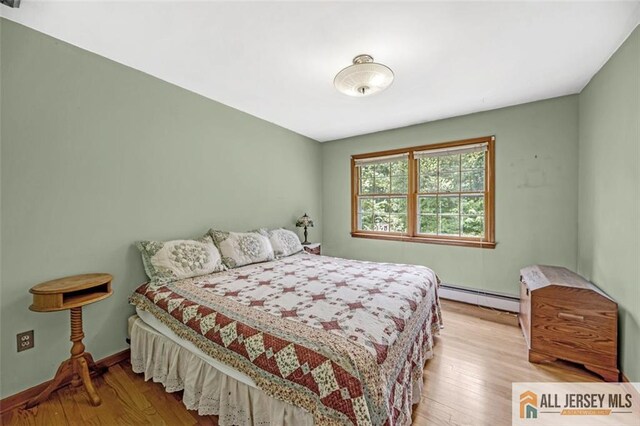 bedroom featuring baseboard heating and light hardwood / wood-style floors