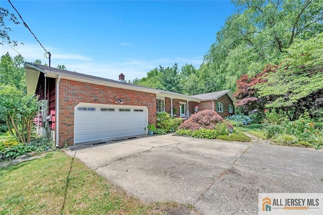 single story home with concrete driveway, an attached garage, brick siding, and a chimney