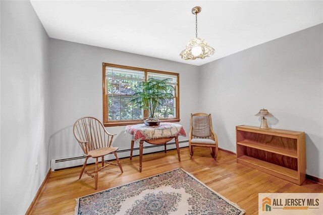 living area featuring a chandelier, wood-type flooring, and a baseboard radiator