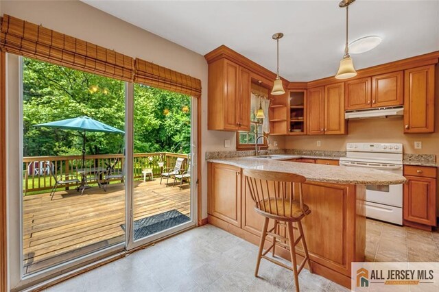 kitchen featuring electric stove, kitchen peninsula, sink, light stone countertops, and a breakfast bar area