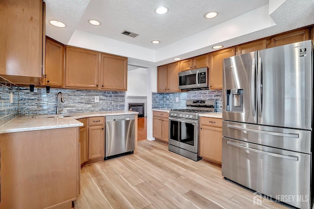 207 Manahan Rd, East Brunswick, NJ 08816 - kitchen featuring appliances with stainless steel finishes, light wood-style floors, light stone countertops, decorative backsplash, and recessed lighting