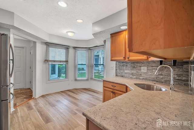 207 Manahan Rd, East Brunswick, NJ 08816 - kitchen with freestanding refrigerator, a textured ceiling, backsplash, light stone counters, and light wood-type flooring